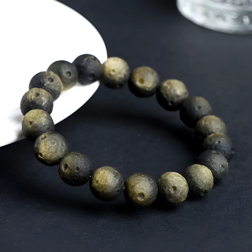 Natural obsidian crater ball bracelet showing polished spherical beads in silver stone meteorite colour with visible mineral texture