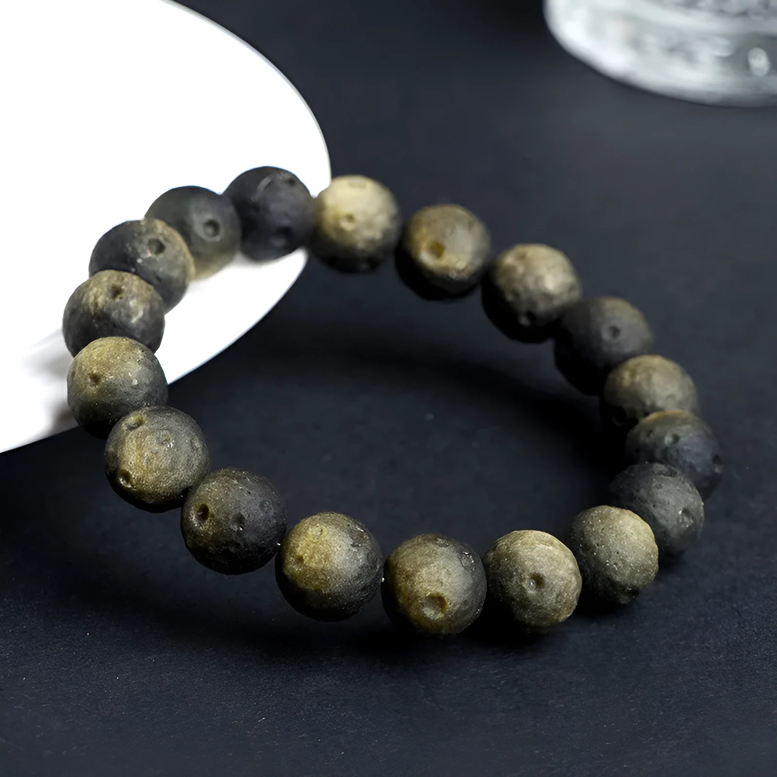 Natural obsidian crater ball bracelet showing polished spherical beads in silver stone meteorite colour with visible mineral texture