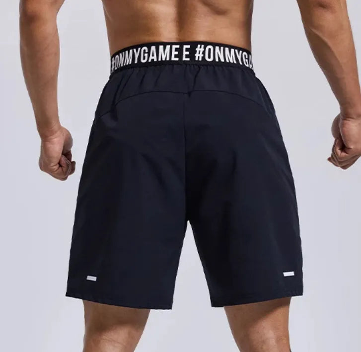 Men's loose fit black sports shorts with an elastic waistband, shown from the front.