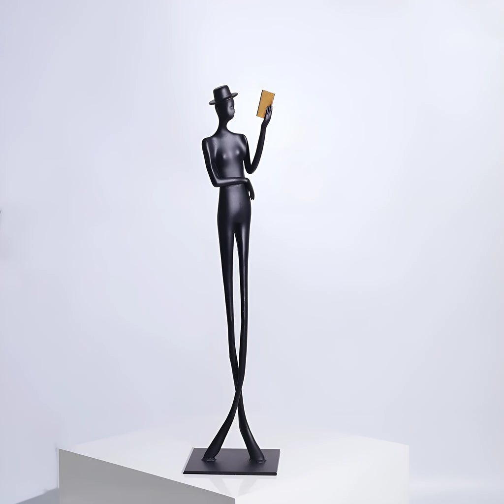 Black cast aluminium sculpture of a reading woman on a desktop, 51 cm tall.