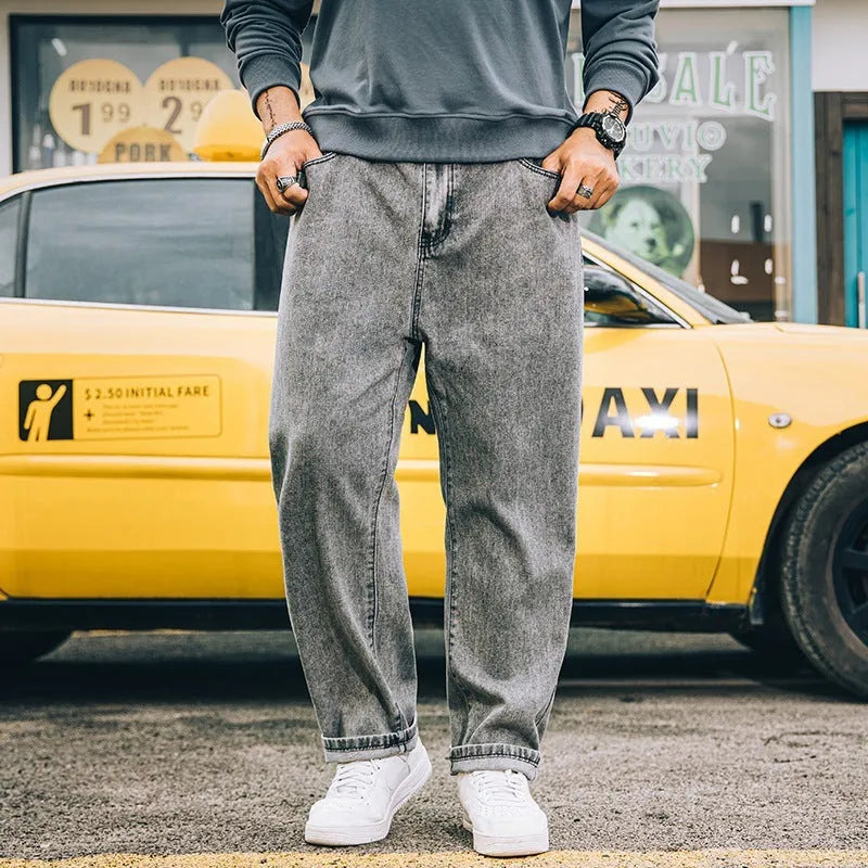 Men's loose straight-cut blue jeans on a plain background, showing the mid waist and zipper fly detail.