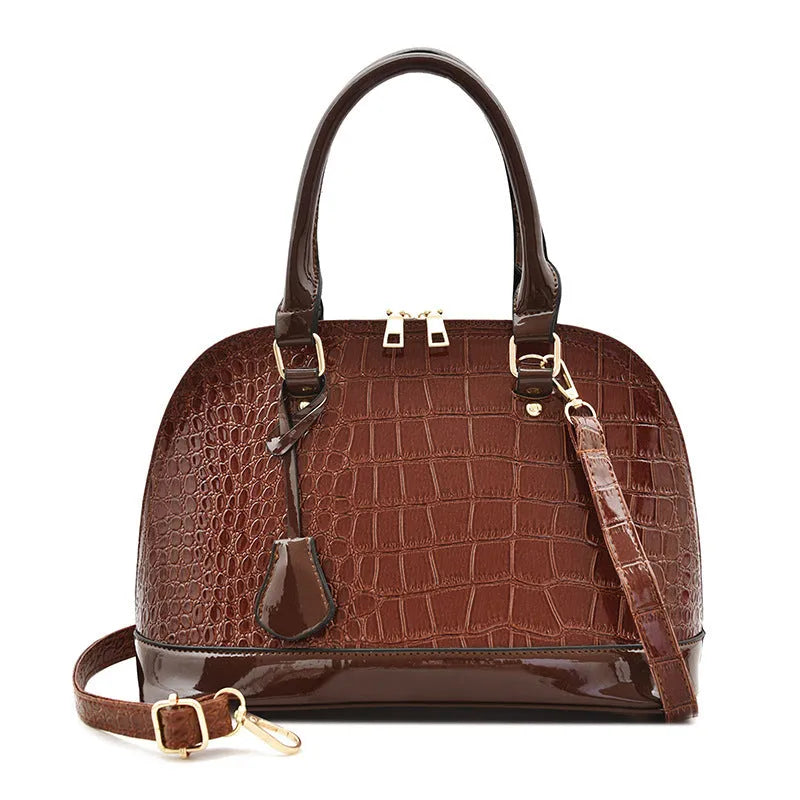 Large shiny black crossbody shoulder bag showing structured shell shape and dimensions