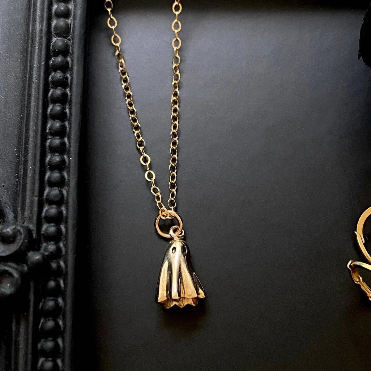 A ghost pendant necklace on a twisted stainless steel chain, showing the titanium steel electroplated pendant.