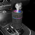 Compact white diamond car air purifier and humidifier unit with USB cable on a car dashboard.