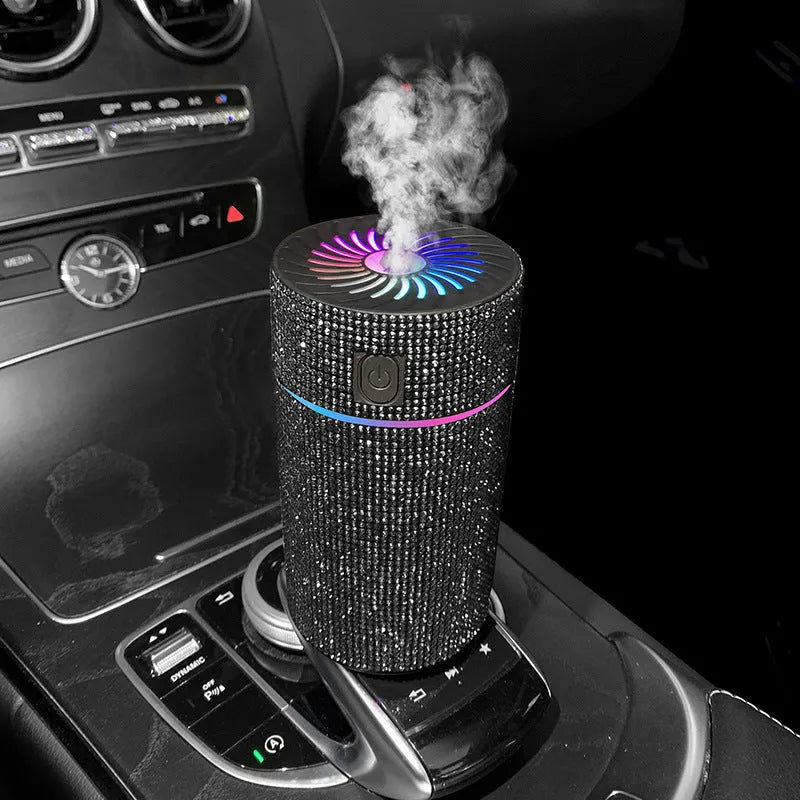 Compact white diamond car air purifier and humidifier unit with USB cable on a car dashboard.