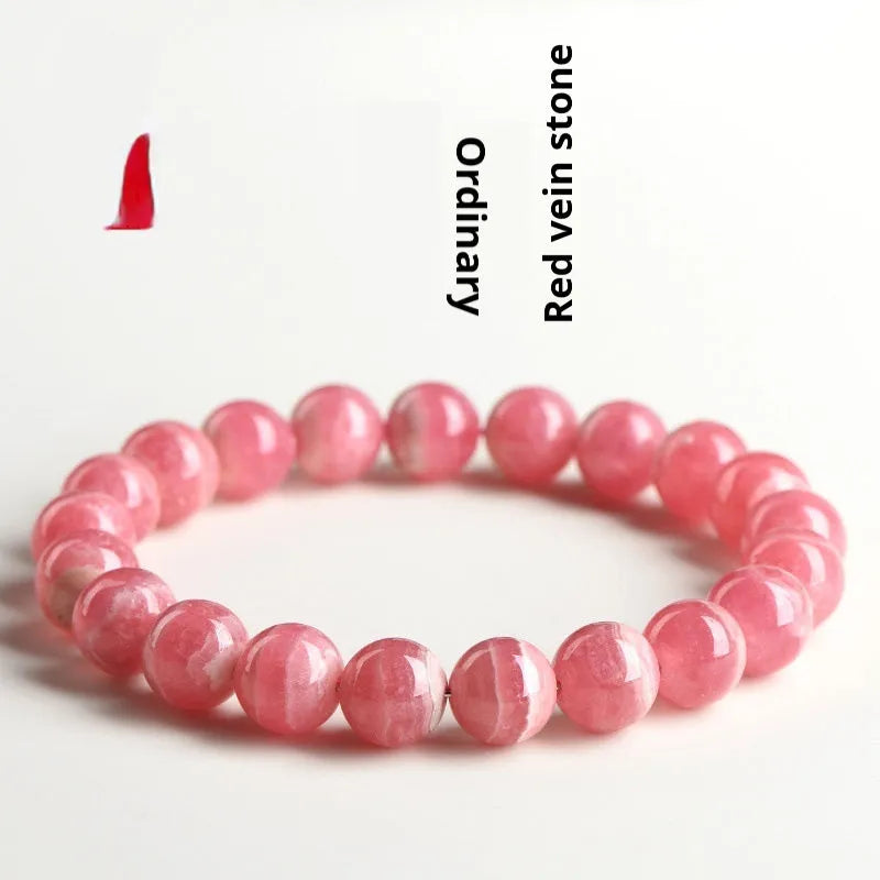 Women's geometric red rhodochrosite crystal bracelet with a longevity lock clasp on a wrist.
