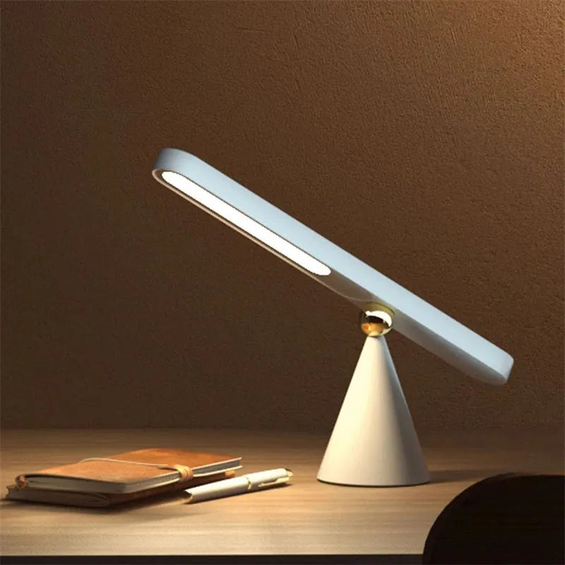Geometric design table lamp with magnetic base on desk next to USB cable