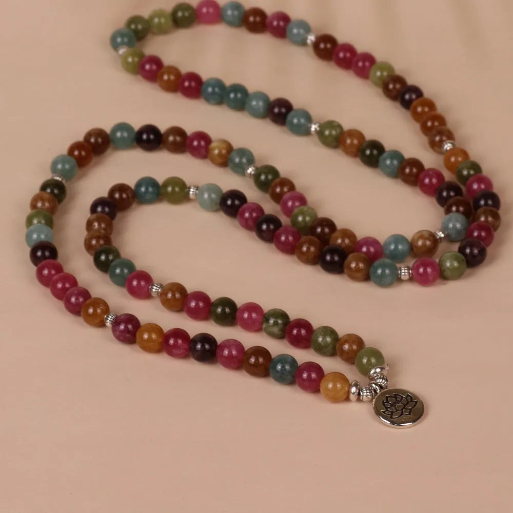 Multi-layer beaded bracelet with 108 tourmaline beads, lotus charm, and alloy clasp on a wrist.