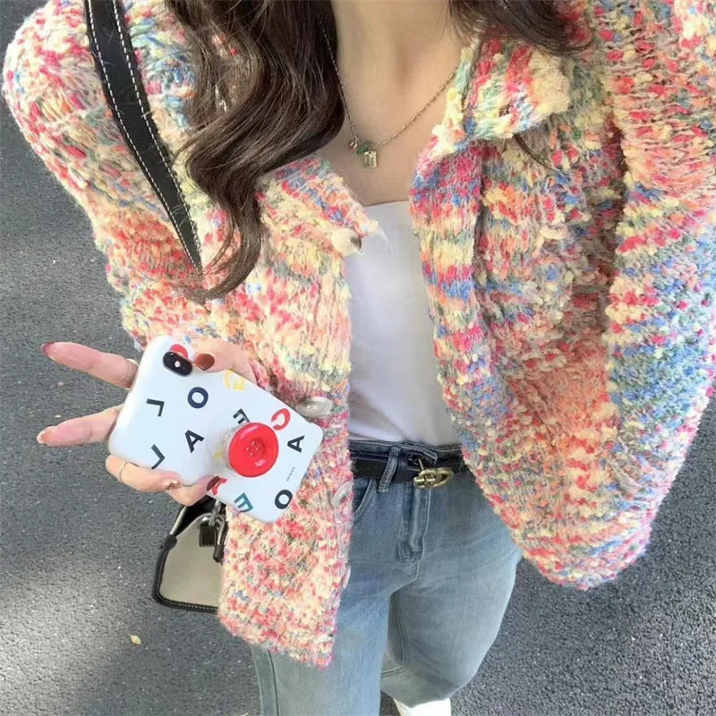 Pink and green retro rainbow patterned knitted cardigan sweater on a hanger.