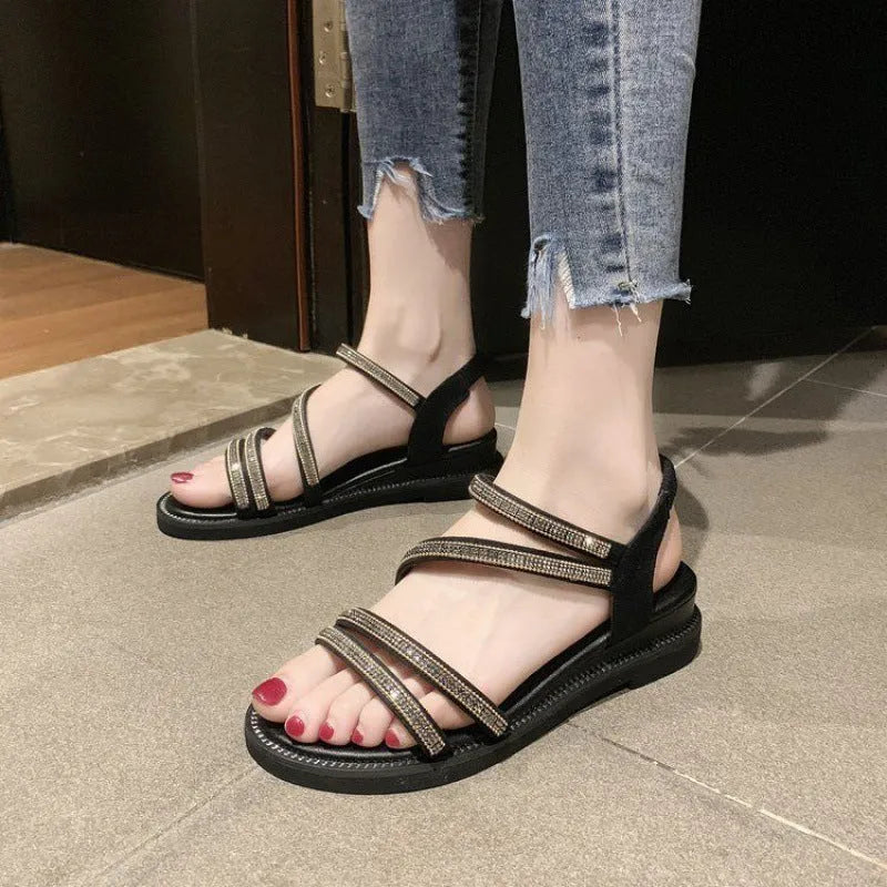 Women's silver flat sandals with rhinestone decoration and elastic band, showing the round toe and rubber sole.