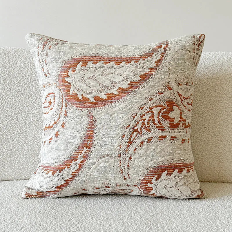 Amber jacquard paisley pillow cover on a sofa, showing textured fabric and botanical pattern.
