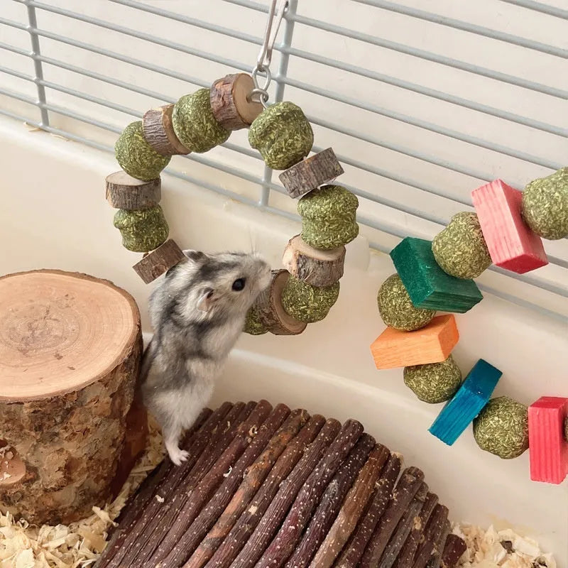 Hamster toy with woven straw ball ring and attached chew rod, shown in two colour variants.