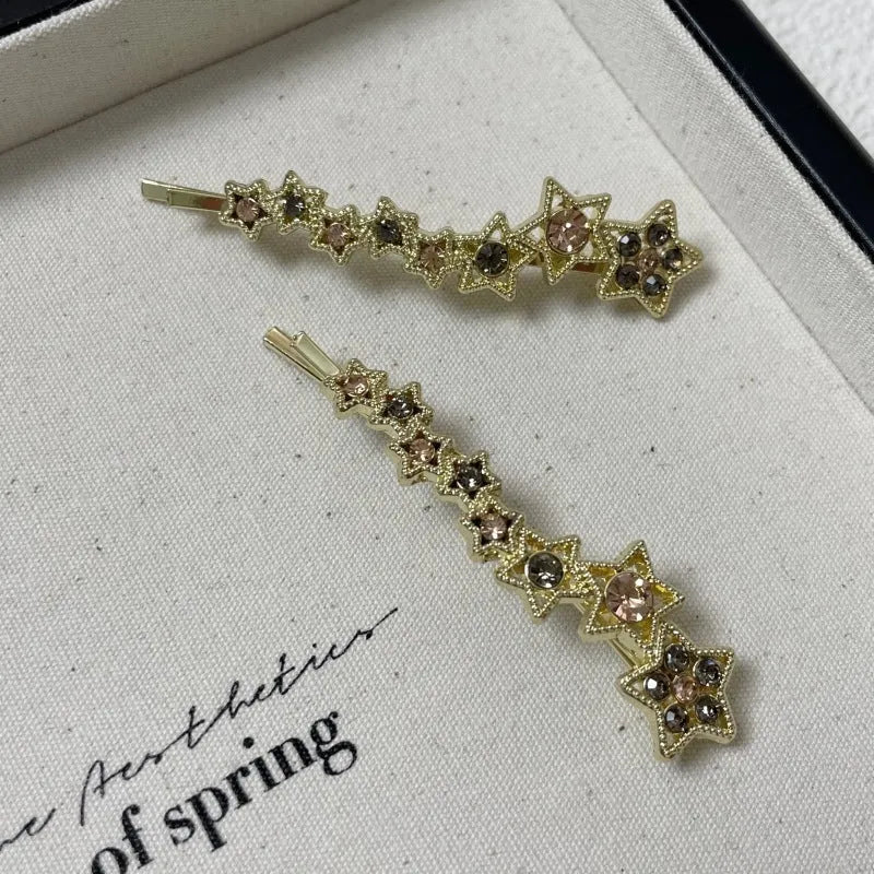 Golden hair clip barrette with a rhinestone five-pointed star, shown on a side angle.
