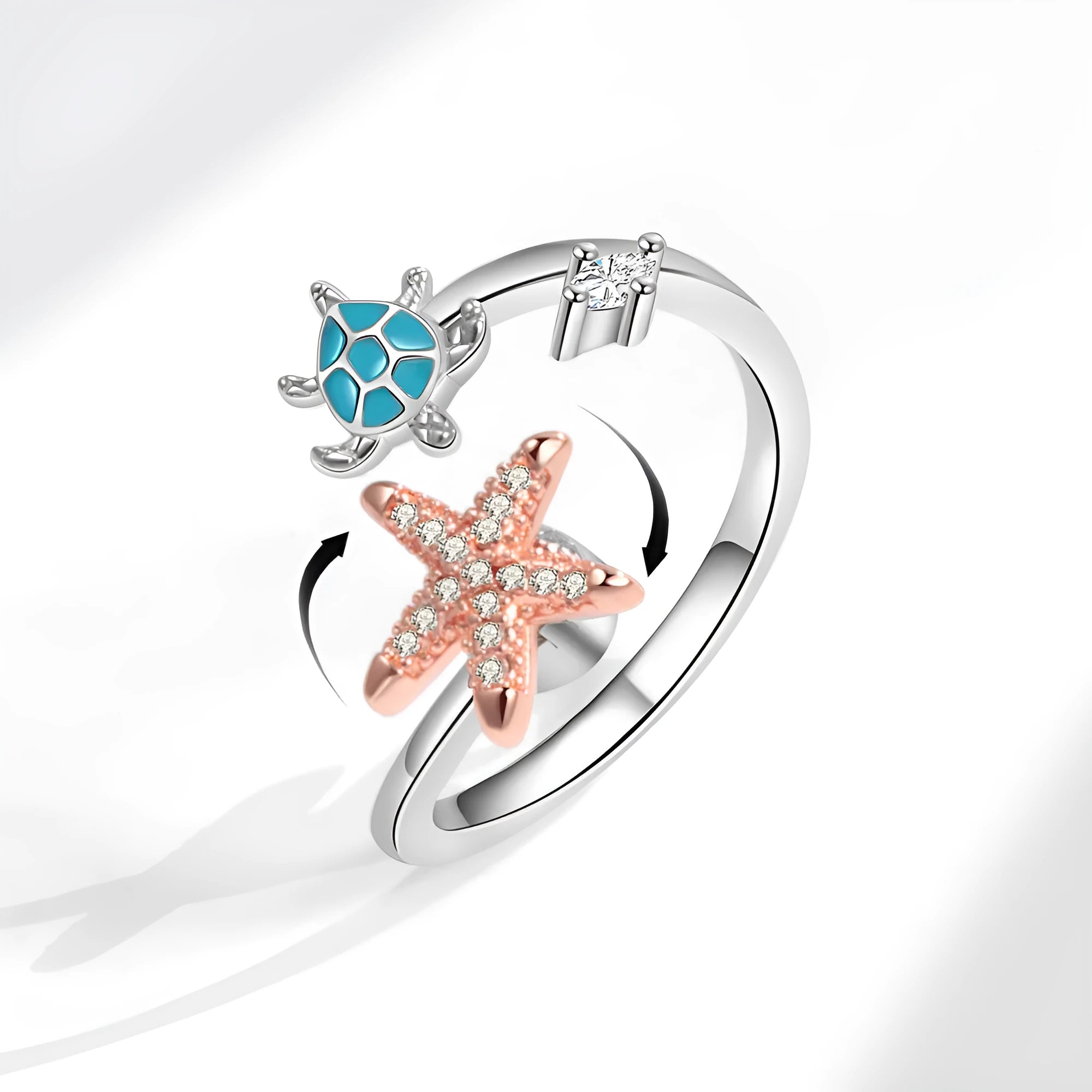 White gold copper spinning anxiety relief ring with turtle and starfish elements on a flat surface