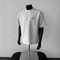 Man wearing a loose fit black short sleeve cotton T-shirt with a white graphic letter print.