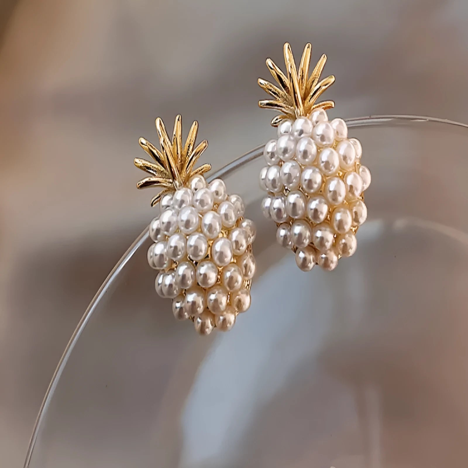 Women's gold electroplated alloy drop earrings with pineapple design and starfish pearl, featuring inlaid stones.
