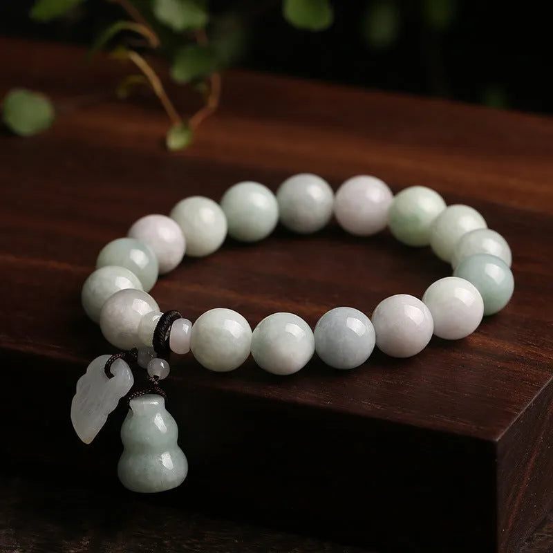 Natural green jade bracelet with Maitreya Buddha charm pendant on a wrist.