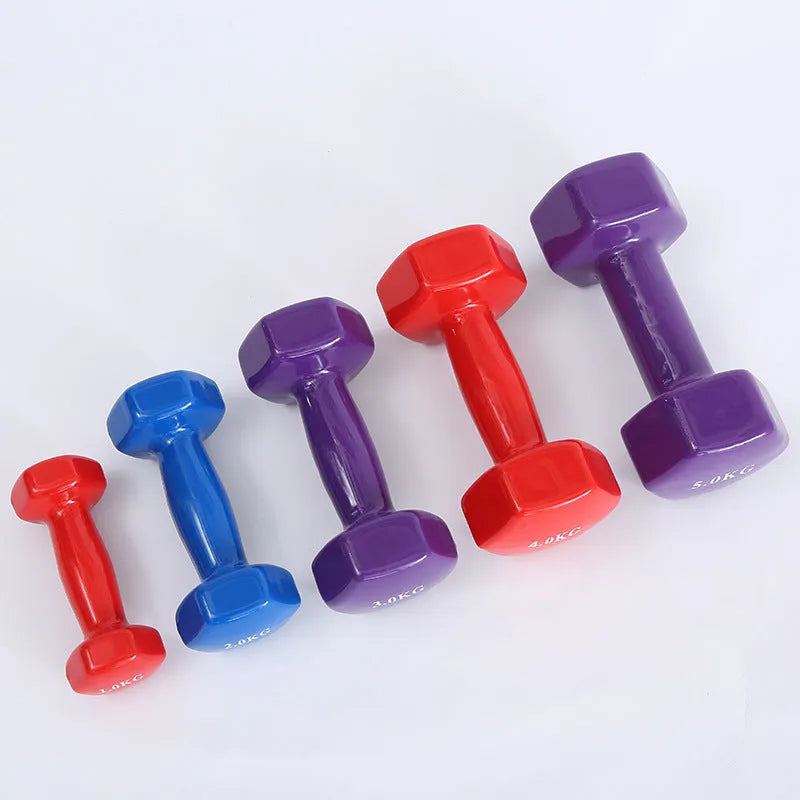 A set of bright green and pink plastic fitness dumbbells on a wooden floor.