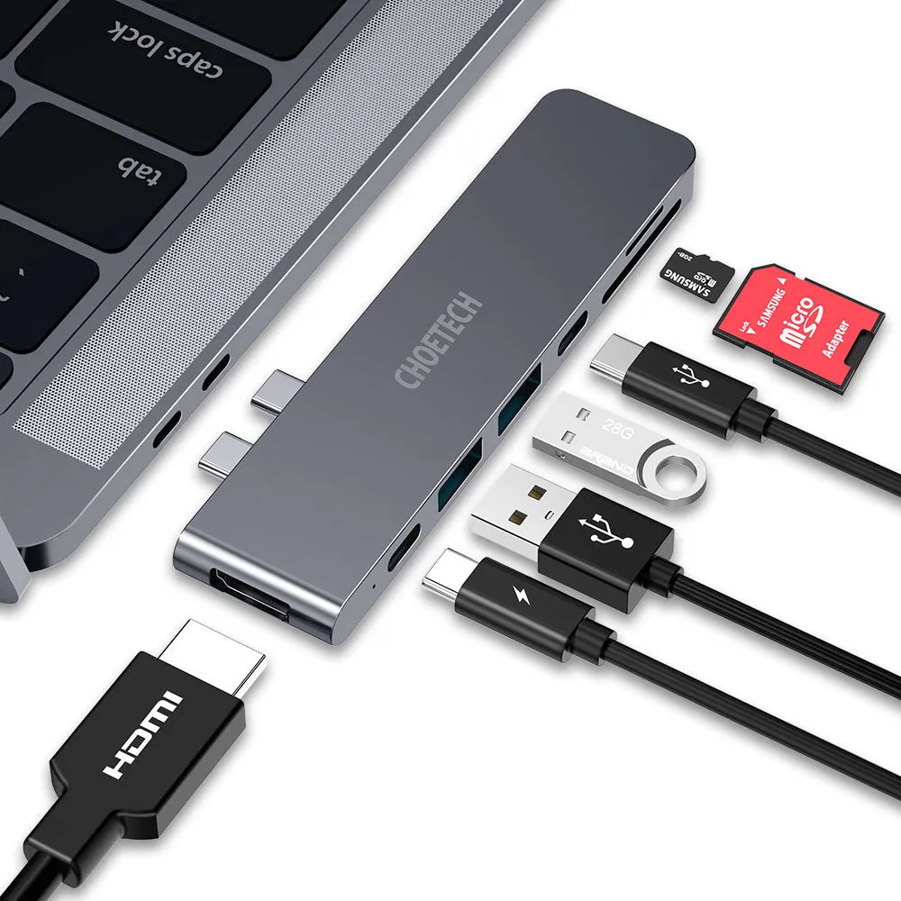Silver 7-in-1 USB-C hub adapter with SD card reader, HDMI, and USB ports on a wooden desk.