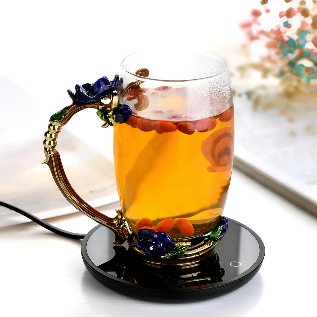 Black coffee mug warmer with temperature switch on desk next to ceramic cup