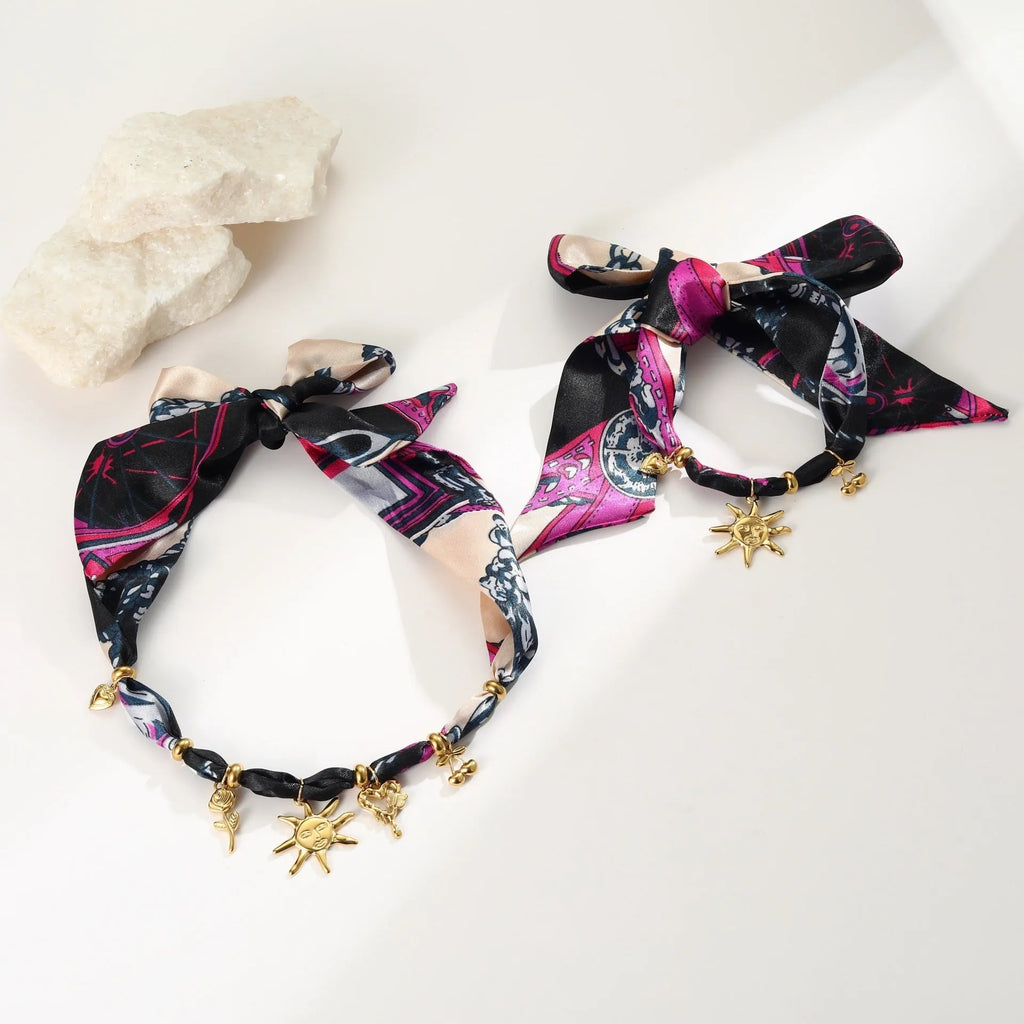 Geometric sun pendant on a gold chain, shown as both a women's necklace and bracelet on a grey background.