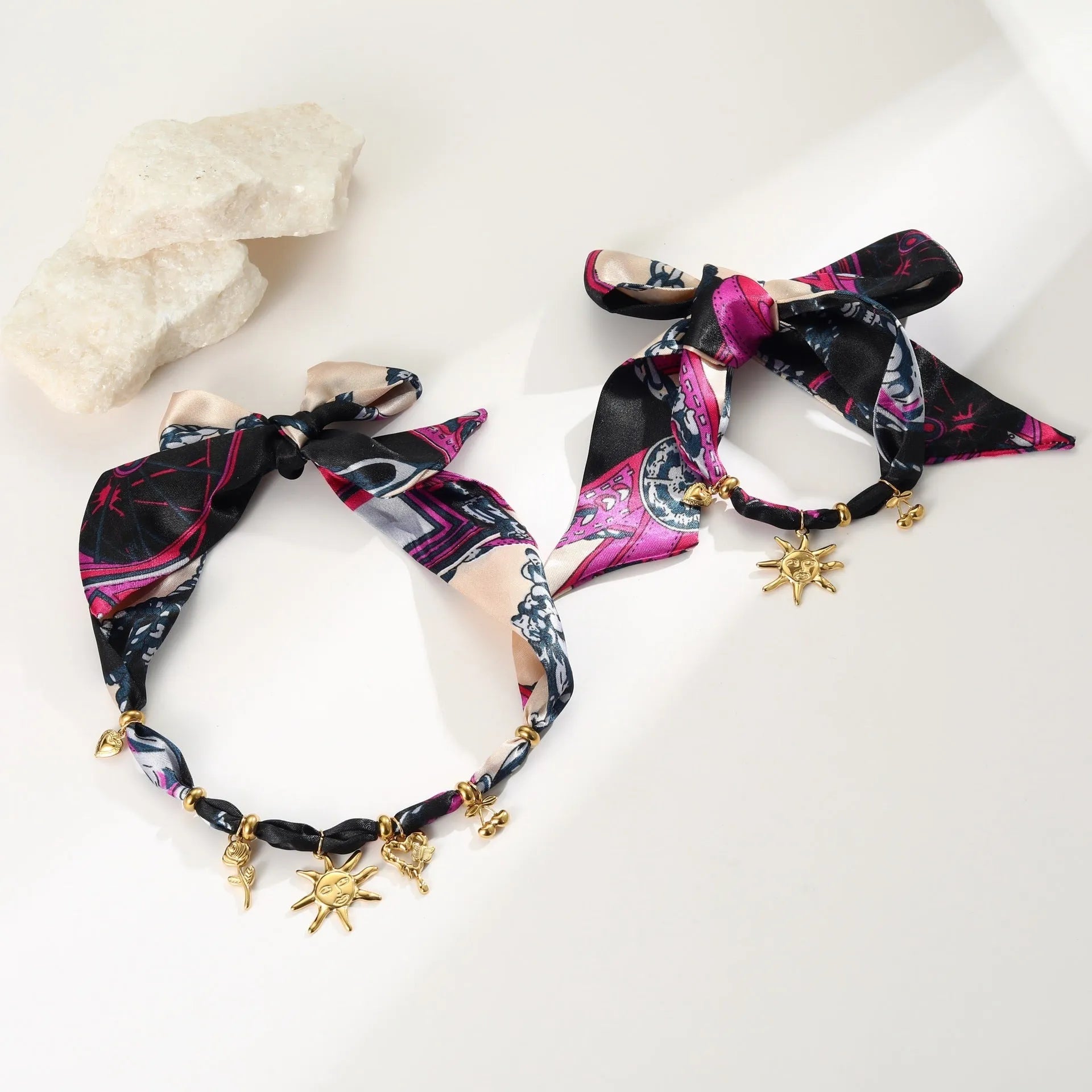 Geometric sun pendant on a gold chain, shown as both a women's necklace and bracelet on a grey background.