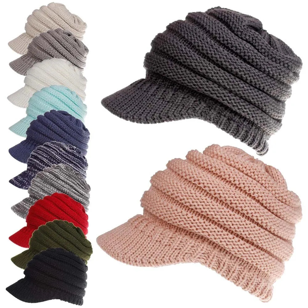 Woman wearing a light grey knitted beanie with a ponytail pulled through the back opening.