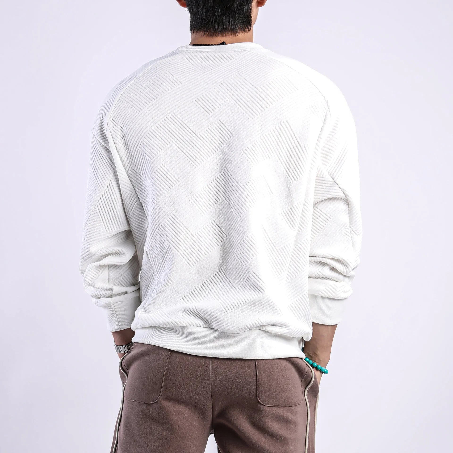 Man wearing a loose-fit, solid-colour twill jacquard long-sleeved sweater with a round neck.