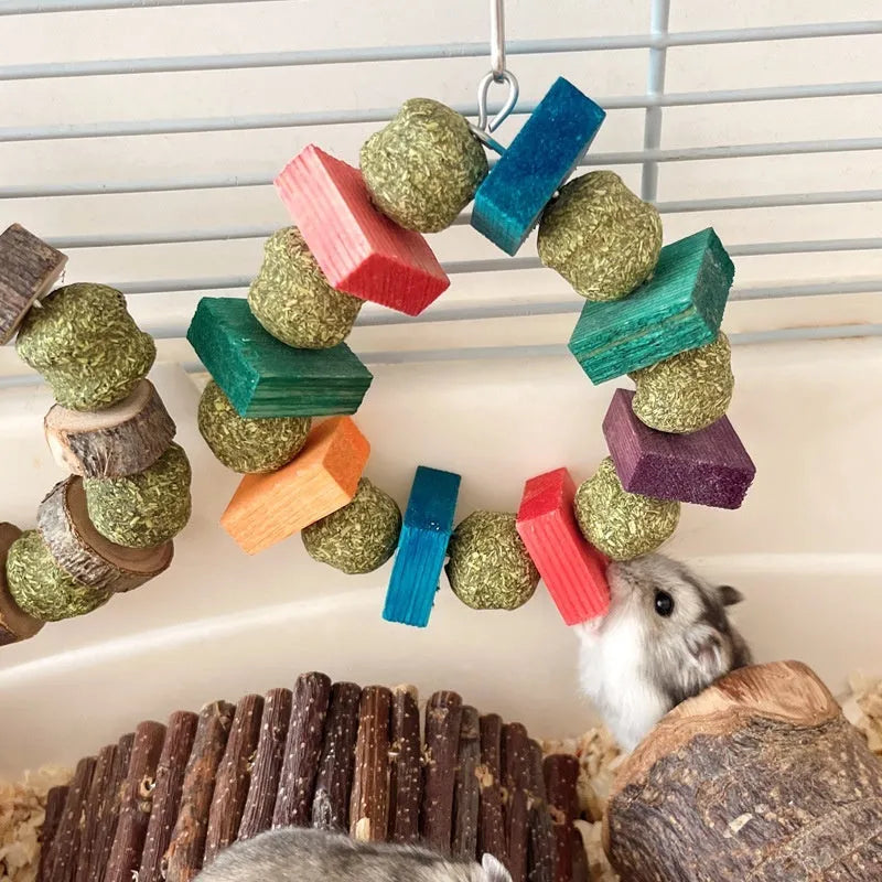 Hamster toy with woven straw ball ring and attached chew rod, shown in two colour variants.