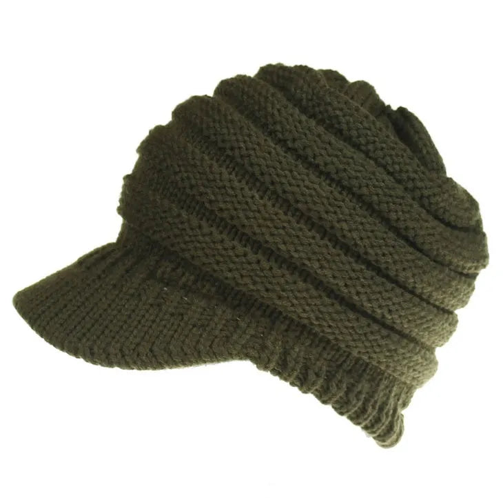 Woman wearing a light grey knitted beanie with a ponytail pulled through the back opening.