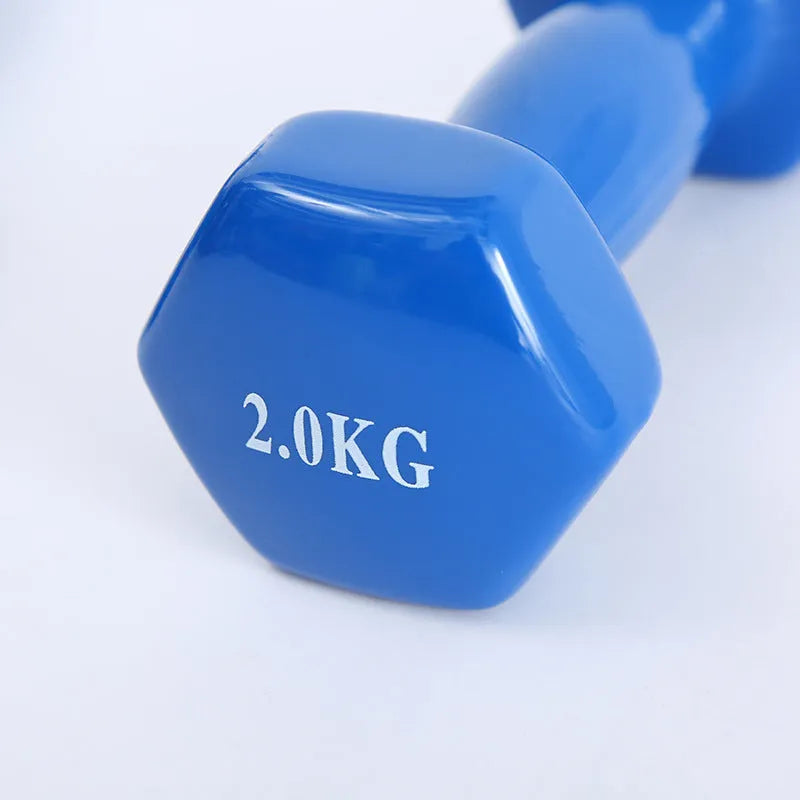 A set of bright green and pink plastic fitness dumbbells on a wooden floor.