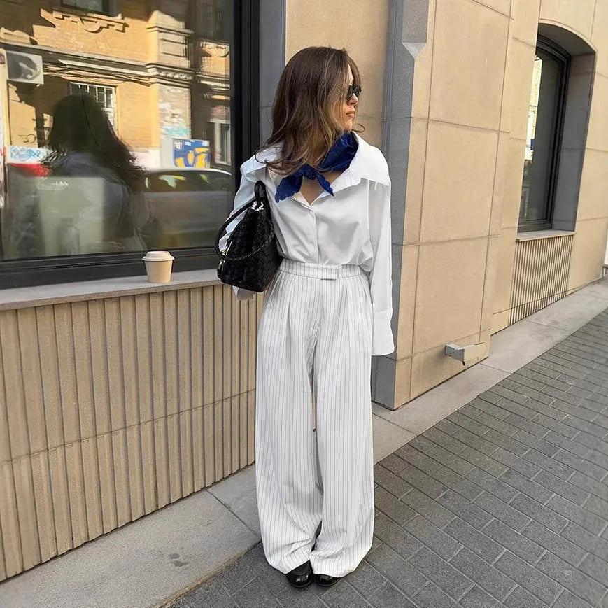White striped wide-leg women's trousers with side zip, laid flat to show loose fit and pattern.