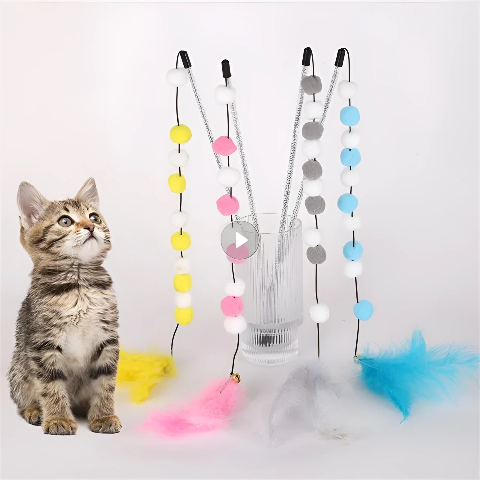 Colourful cat teaser toy rod with bell and pompon feather attachment on grey background