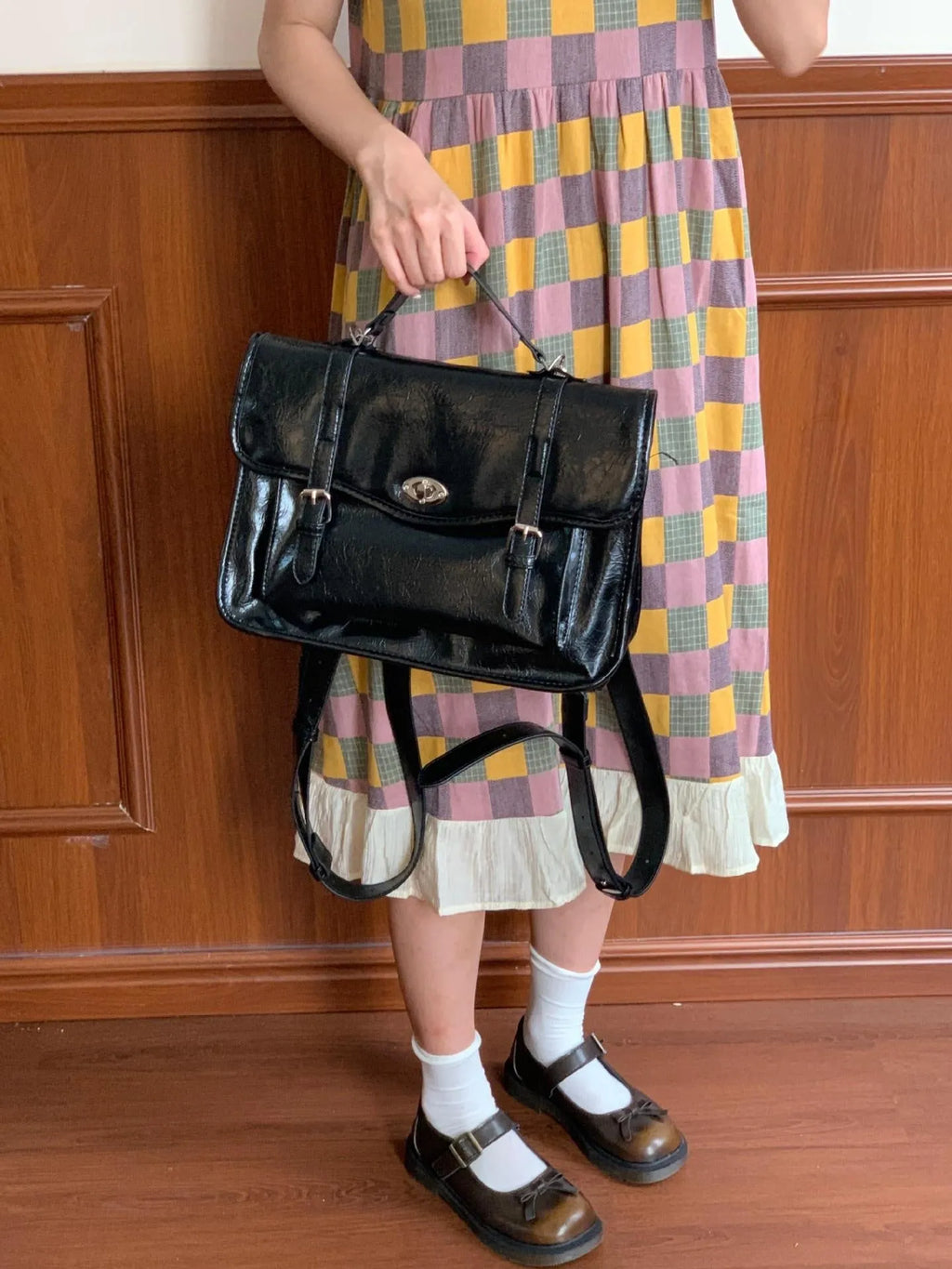 Black college style messenger bag with oil wax leather finish showing shoulder strap and 35cm length