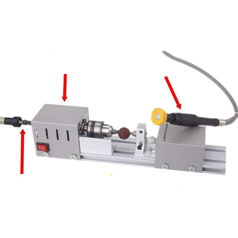 Silver metal mini manual woodworking lathe on a bench with carving knives and accessories.
