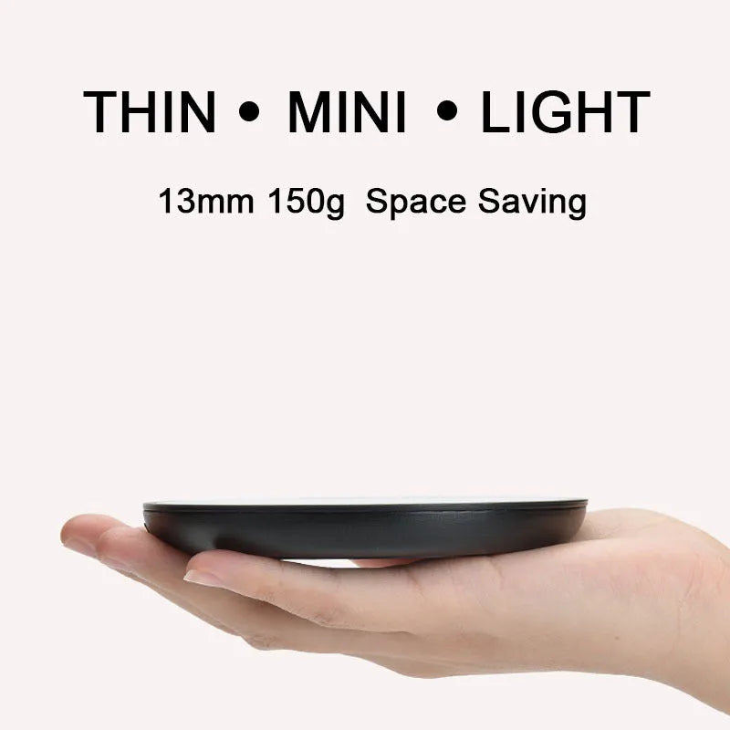 Black coffee mug warmer with temperature switch on desk next to ceramic cup
