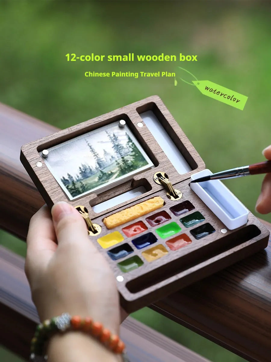 Miniature wooden watercolour paint box on a table, showcasing its compact size and walnut finish.