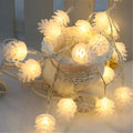 Battery-powered warm white LED pine cone fairy lights draped decoratively on a surface.