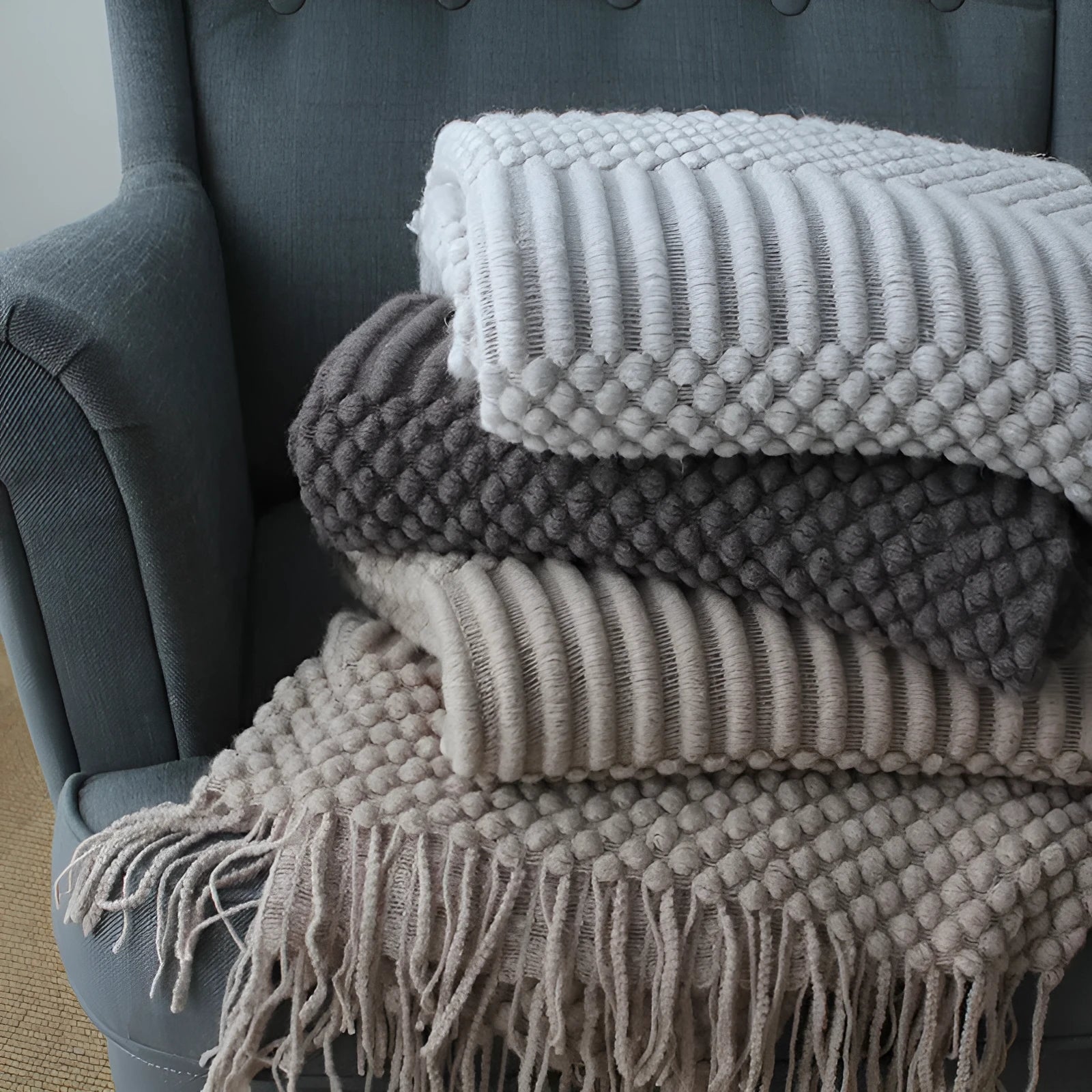 Light grey polyester throw blanket draped over a sofa, showing its size.