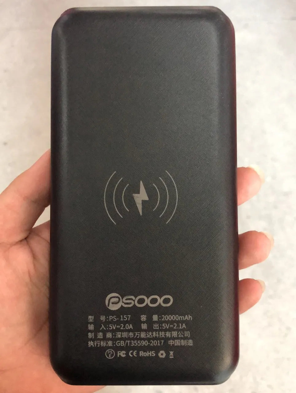 Black solar power bank with wireless Qi charging pad, three USB ports, and an LED flashlight