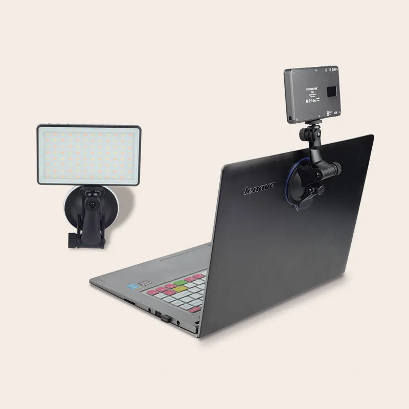 Black aluminium USB LED conference light with screen, shown next to a laptop for video calls.