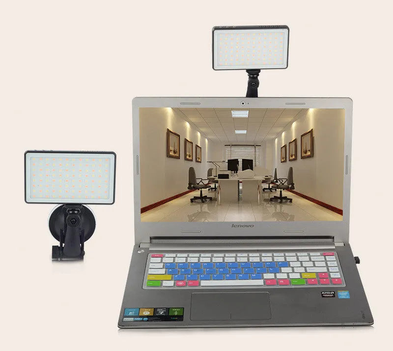 Black aluminium USB LED conference light with screen, shown next to a laptop for video calls.