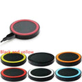 Slim square Qi wireless charging pad in one of six colours on a desk next to a mobile phone.