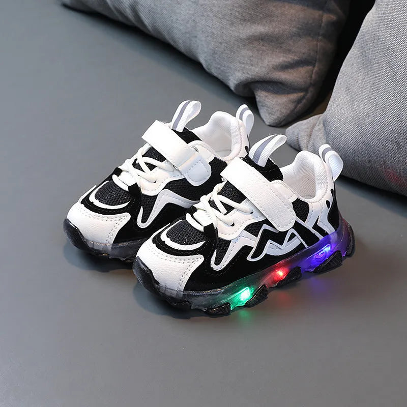 Children's bright coloured sneakers with mesh panels and a Velcro strap fastening, shown in black, pink, and grey.