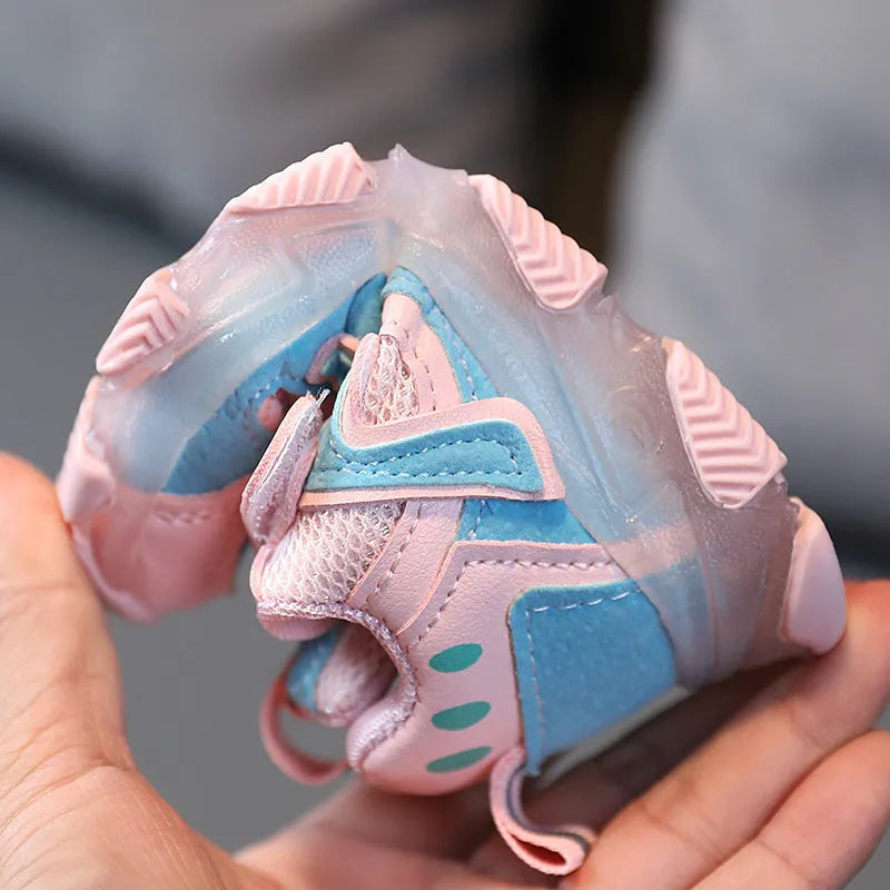 Children's bright coloured sneakers with mesh panels and a Velcro strap fastening, shown in black, pink, and grey.