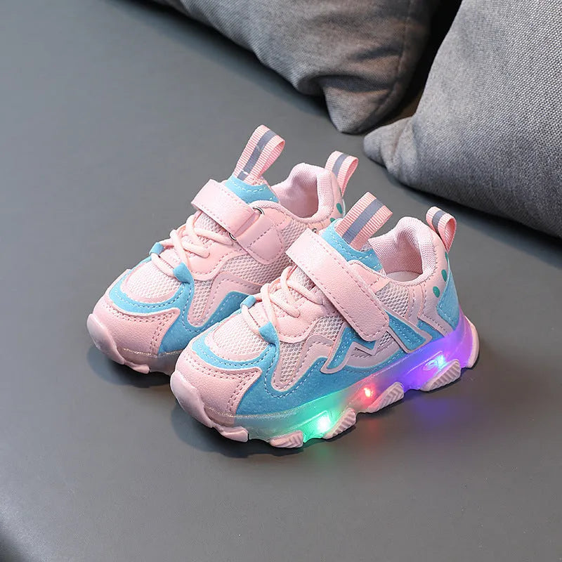 Children's bright coloured sneakers with mesh panels and a Velcro strap fastening, shown in black, pink, and grey.
