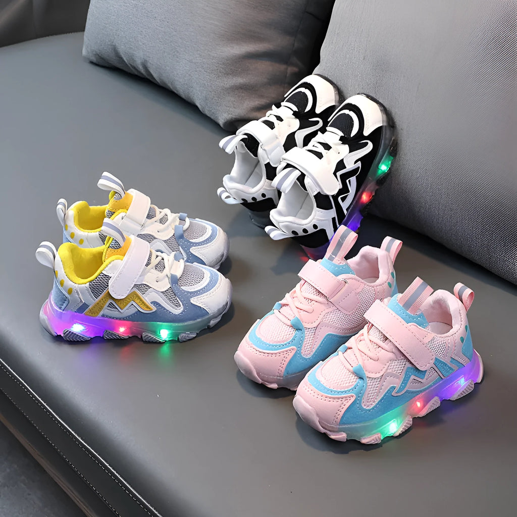 Children's bright coloured sneakers with mesh panels and a Velcro strap fastening, shown in black, pink, and grey.