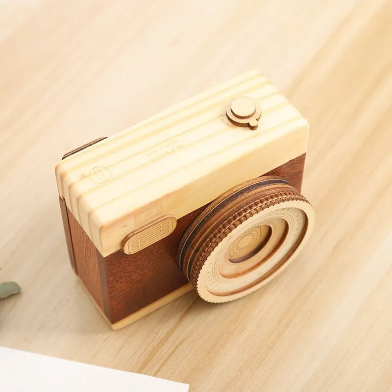 Wooden camera-shaped music box in sanded pine finish, shown in large and small size options.
