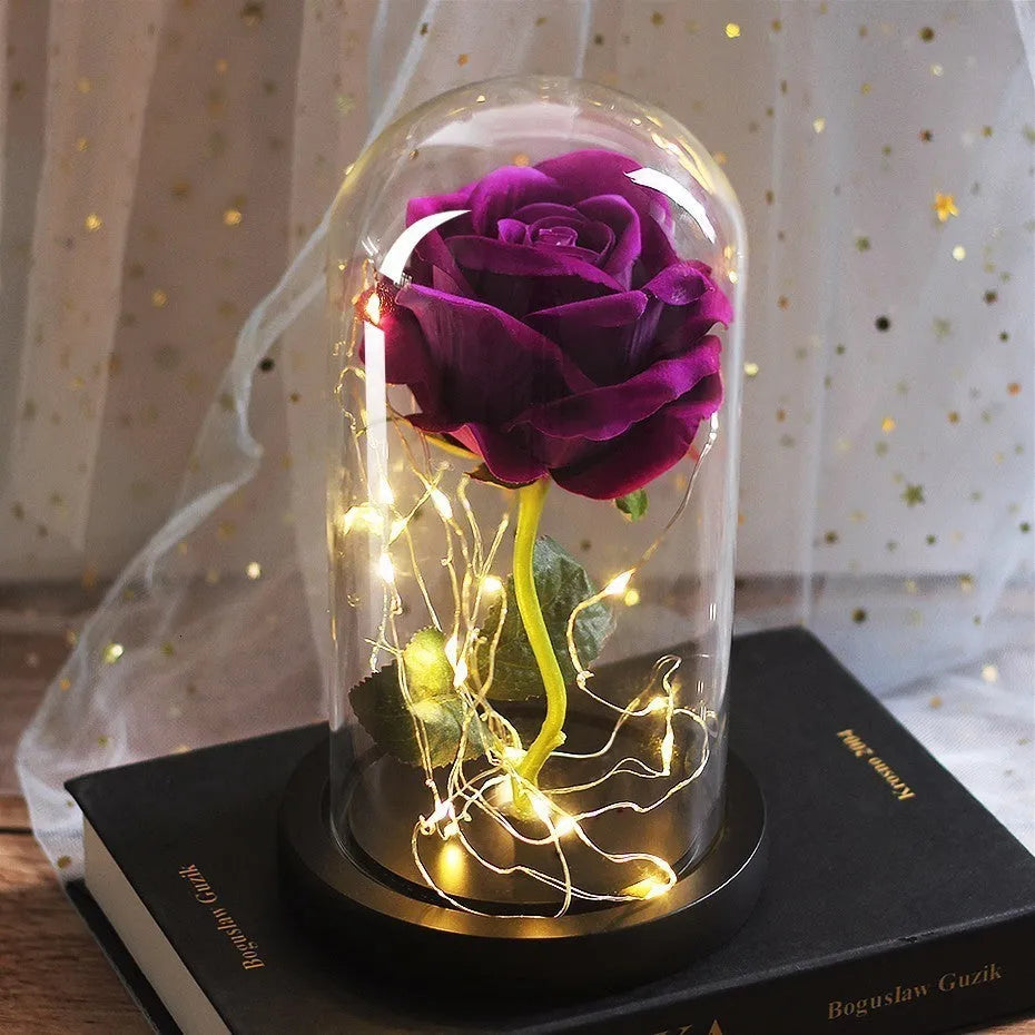 Artificial rose LED bouquet with glass shade and warm white light on a solid wood base.