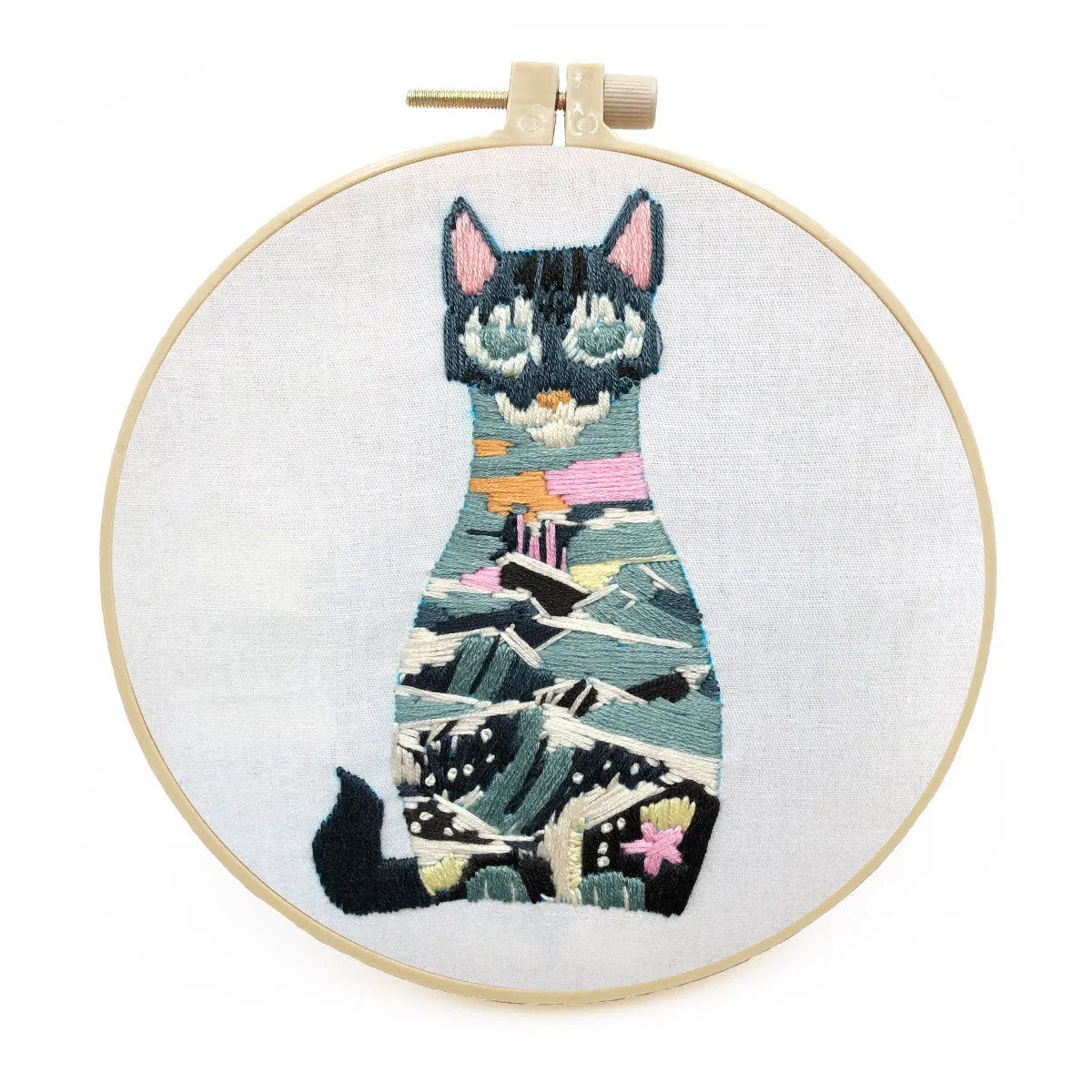 Cross stitch kit for 3D cat embroidery with hoop, fabric, and threads on a wooden table.